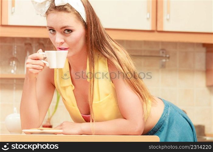 Pretty pin up girl drinking tea or coffee at home. Gorgeous young retro woman with hot beverage relaxing.. Pretty pin up girl drinking tea or coffee at home.