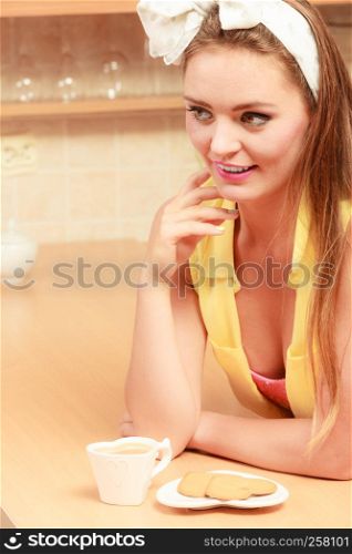 Pretty pin up girl with heart shape gingerbread cookies drinking tea or coffee at home. Gorgeous young retro woman with hot beverage relaxing in kitchen.. Girl with gingerbread cookies drinking tea coffee.