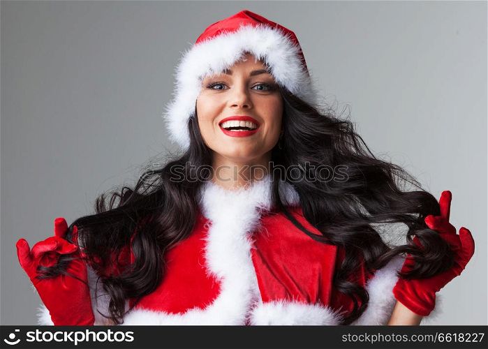 Pretty Pin-up style Santa girl in red clothes on gray background. Pin-up Santa girl