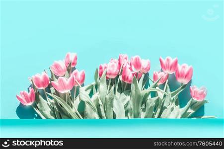 Pretty pink pale tulips flowers bunch at turquoise blue background.