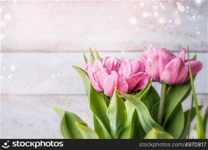 Pretty pink tulips blooming on light wooden background, front view, close up