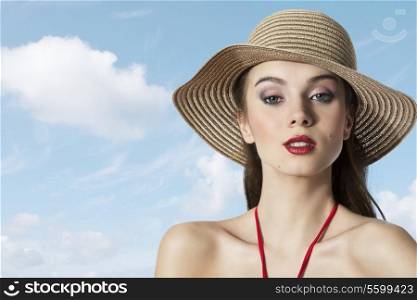 pretty portrait of beautiful young woman with summer hat looking in camera on blue sky. Summer time