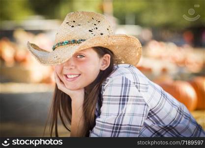 Pretty Preteen Girl Wearing Cowboy Hat Portrait at the Pumpkin Patch in a Rustic Setting.