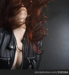 Pretty redhead young woman flipping head back with long hair flying out.