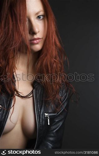 Pretty redhead young woman portrait with leather jacket unzipped showing cleavage.