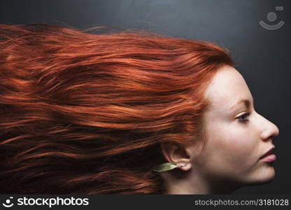 Pretty redhead young woman profile with hair streaming out behind her.