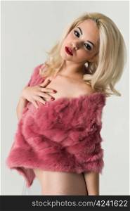 Pretty slender nude blonde in a fake fur coat