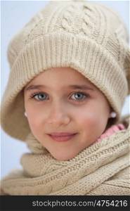Pretty small girl with wool scarf and hat looking at camera