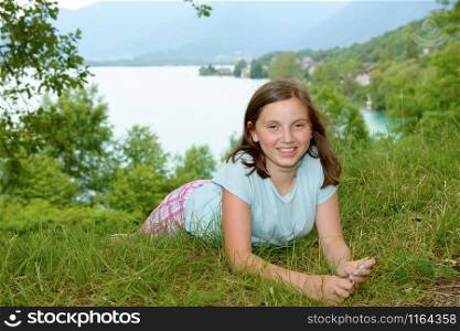 pretty smiling pre teen girl lying in grass