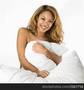 Pretty smiling woman on bed hugging pillow.