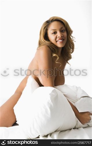 Pretty smiling woman on bed making eye contact.
