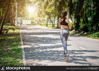 Pretty sport woman jogging in the park, running outdoors in nature