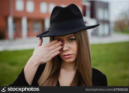 Pretty stylish girl with a hat covering her face with the hands