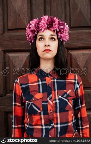 Pretty stylish girl with pink flower crown and red plaid shirt In front of a wooden door