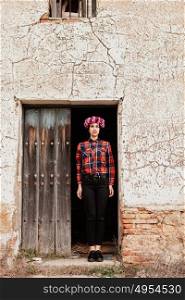 Pretty stylish girl with pink flower crown and red plaid shirt in a old house