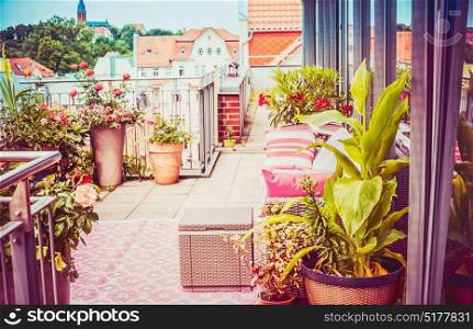 Pretty summer terrace or balcony of penthouse with flowers patio pots , outdoor furniture and nice city view