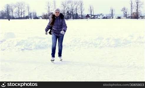 pretty teenage girl goes skating by winter frozen lake