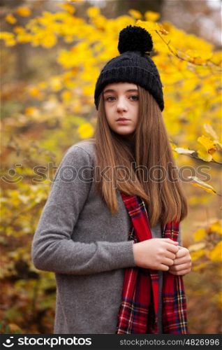 Pretty teenage girl wearing woolen hat with autumnal colours in the background