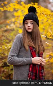 Pretty teenage girl wearing woolen hat with autumnal colours in the background