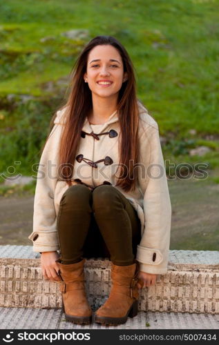 Pretty teenager girl sitting on the sidewalk in a park