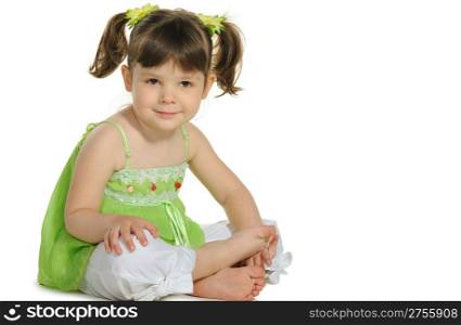 Pretty the little girl sits on the white. It is isolated on a white background