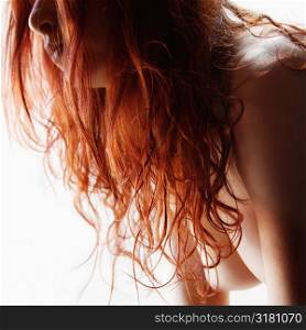 Pretty topless redhead young woman against white background.