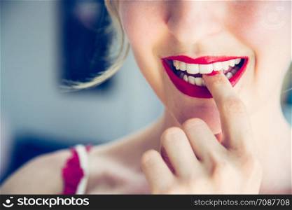Pretty white woman with red sensual lipstick and colorful nail polish is looking into the mirror, cut out