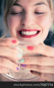 Pretty white woman with red sensual lipstick and white teeth colorful nail polish is looking into the mirror.