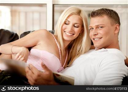 Pretty woman and handsome male reading a book and smiling