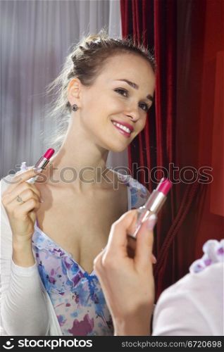 Pretty woman applying her make-up looking at mirror