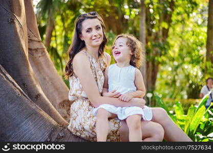 Pretty woman carrying her beloved children in a tropical park