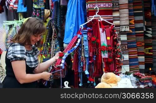 pretty woman chooses Ukrainian folk ornaments on souvenir market