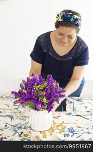 Pretty woman decorating her home table with a beautiful flower arrangement