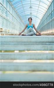 Pretty woman doing meditating yoga exercises outdoors on the bridge