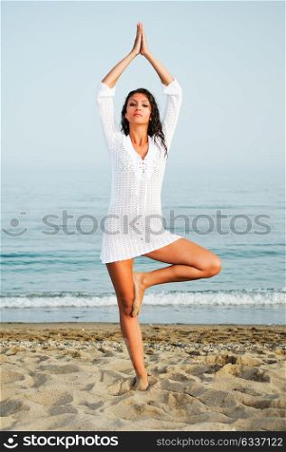 Pretty woman doing yoga on the beach