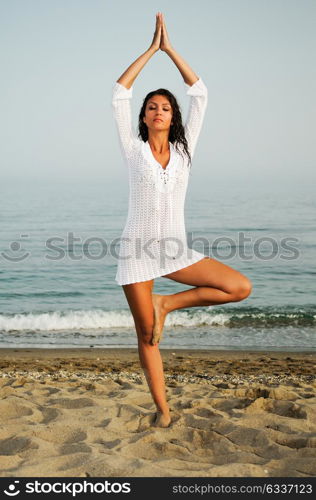 Pretty woman doing yoga on the beach