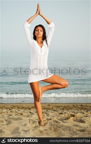 Pretty woman doing yoga on the beach