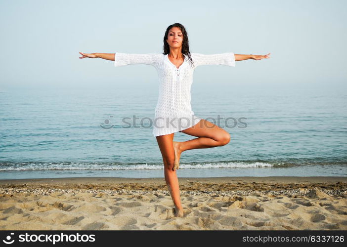 Pretty woman doing yoga on the beach