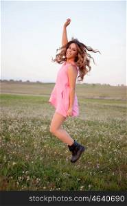 Pretty woman dressed in pink jumping on a flowery meadow