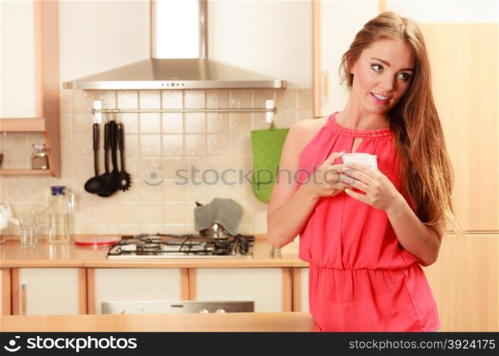 Pretty woman drinking tea or coffee at home.. Pretty woman drinking tea or coffee at home. Gorgeous young girl with hot beverage relaxing in kitchen.