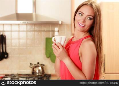 Pretty woman drinking tea or coffee at home.. Pretty woman drinking tea or coffee at home. Gorgeous young girl with hot beverage relaxing in kitchen.