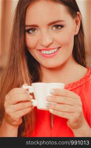 Pretty woman drinking tea or coffee at home. Gorgeous young girl with hot beverage relaxing in kitchen.