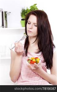 pretty woman eating salad. pretty young woman about to eat salad in her kitchen