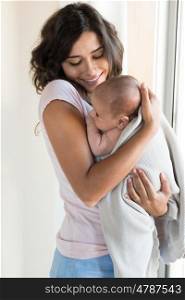 Pretty woman holding a newborn baby in her arms