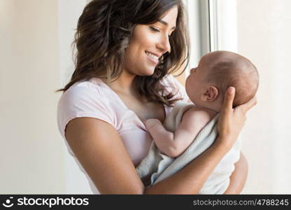 Pretty woman holding a newborn baby in her arms