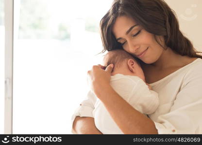 Pretty woman holding a newborn baby in her arms