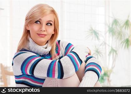 pretty woman in a beauty fashion shot wearing a colored warm and comfortable sweater thinking against white background