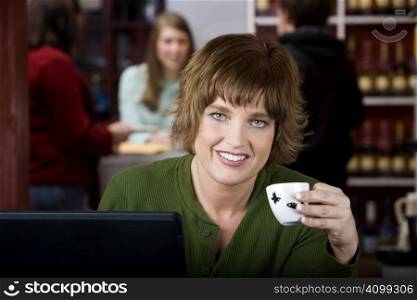 Pretty woman in a cafe with earphones and a laptop computer