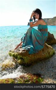 Pretty woman in dress on the sea rock