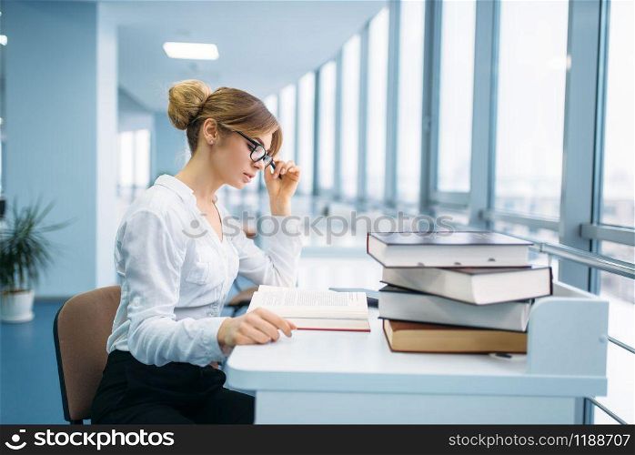 Pretty woman in glasses learning book in library. Female person in reading room, knowledge depository. Pretty woman in glasses learning book, library